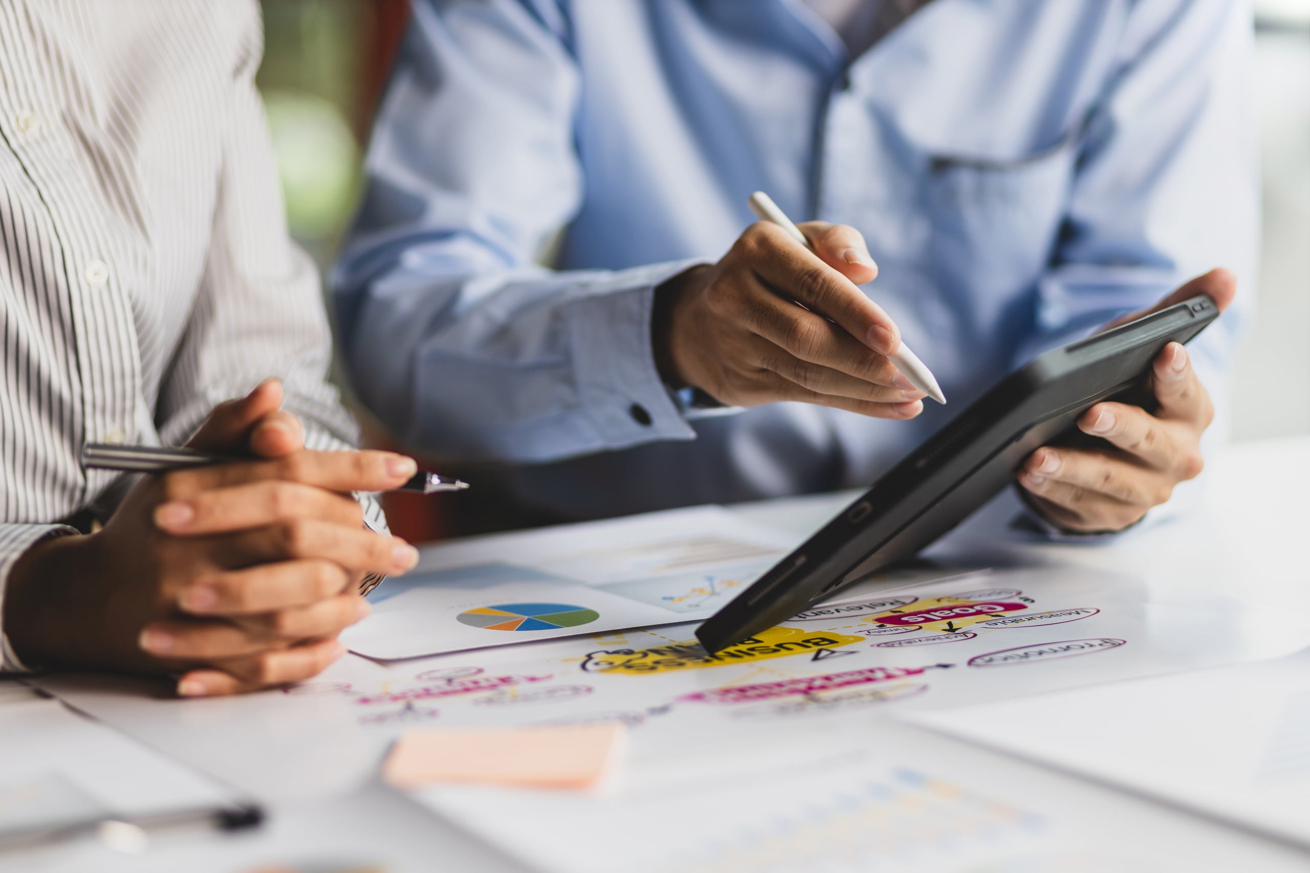 Person writing strategy notes beside a laptop and coffee
